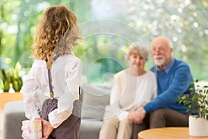 blond child standing with gift behind her back on the grandparent`s day