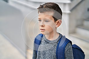 Blond child student standing with serious expression at school