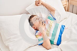 Blond child waking up lying on bed at bedroom