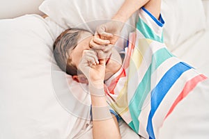 Blond child waking up lying on bed at bedroom