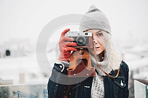 Blond curly girl with film photo camera, winter