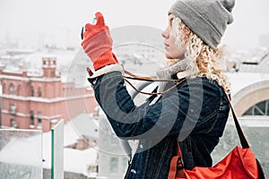 Blond curly girl shooting on film photo camera, winter