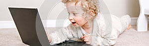 Cute blond curly toddler baby boy working on laptop. Little kid child using technology. Early age education development. Video