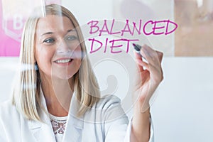 Blond dietitian holds a marker and writes on a glass board