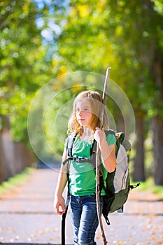 Blond explorer kid girl walking with backpack in autumn trees