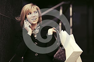 Blond fashion woman with shopping bags calling on cell phone