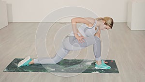 Blond female athlete lunging and stretching in studio