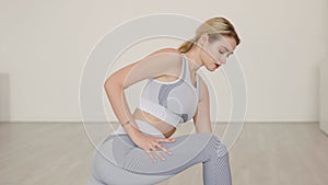 Blond female athlete lunging and stretching in studio