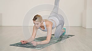 Blond female athlete lunging and stretching in studio