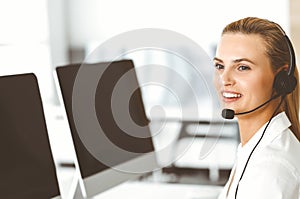 Blond female customer service representative is consulting clients online using headset. Call center and business