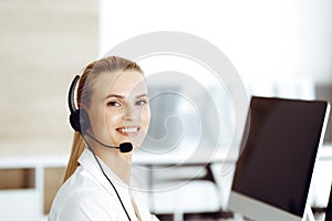 Blond female customer service representative is consulting clients online using headset. Call center and business