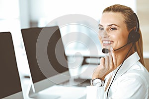 Blond female customer service representative is consulting clients online using headset. Call center and business