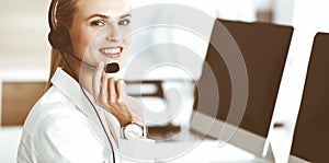 Blond female customer service representative is consulting clients online using headset. Call center and business