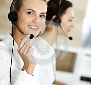 Blond female customer service representative and her colleague are consulting clients online using headset. Call center