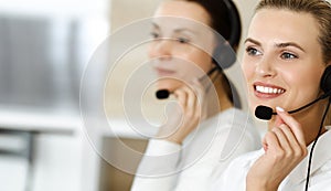 Blond female customer service representative and her colleague are consulting clients online using headset. Call center