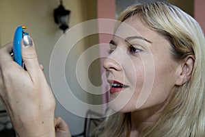 Blond female model looking into a makeup compact mirror