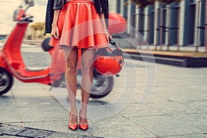 Woman`s legs near red scooter.