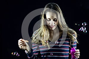 Blond female teenager looking down playing with soap bubbles