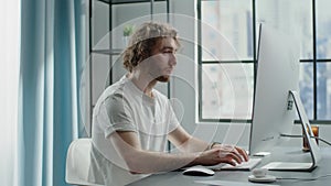 Blond freelancer works on computer and chats on smartphone