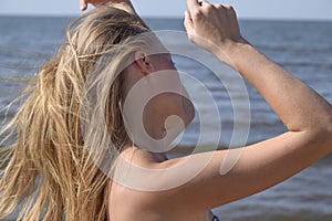 Blond girl in a bikini on the beach. Beautiful young woman in a colorful bikini on sea background