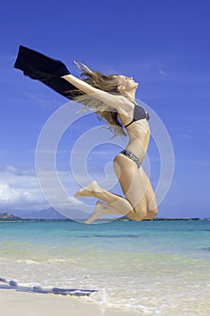 Blond girl in bikini jumping at the beach