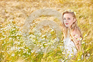 Blond girl on the camomile field