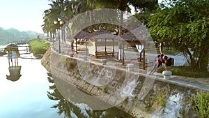 Blond girl does fitness on riverfront with palms