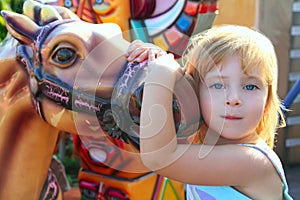 Blond girl with fairground horse enjoy in park photo
