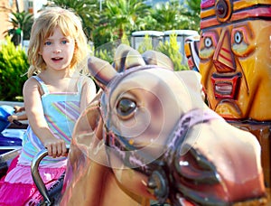 Blond girl with fairground horse enjoy in park photo