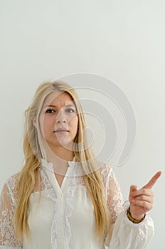 Blond girl is frowning eyebrows and lifting her index finger pointing