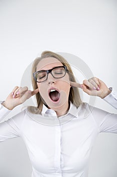 Blond girl in glasses with fingers in ears