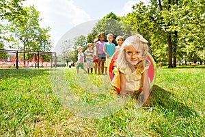 Blond girl and her friends play in tube on lawn