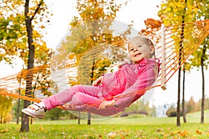 Blond girl laying on net of hammock in park