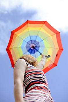 Blond girl looking up in blue sky under colorfull