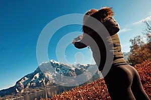 Blond girl is making picture of huge mountain and lake in the central of Europe by phone