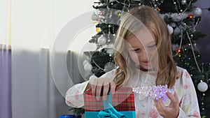 Blond girl opens present in the Christmas morning