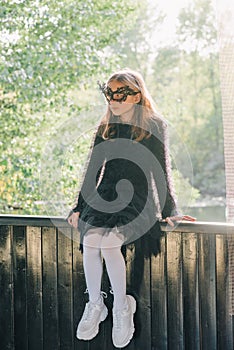 Blond girl outdoors. Halloween. Teenage girl in park. Girl in a masquerade mask/ Portrait of a beautiful girl teenager