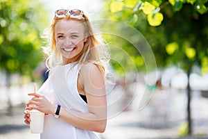 Blond girl in park with fresh drink