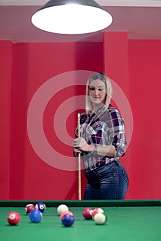 Blond girl is playing pool