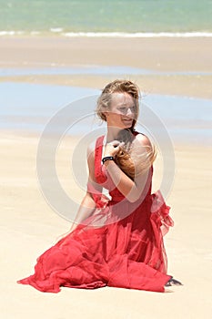 Blond girl with red dress sitting on beach