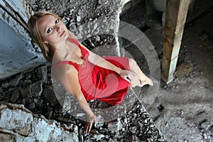 Blond girl sitting on edge in abandoned building