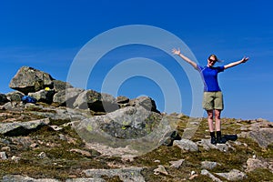 Blond girl with sunglasses wearing athletic clothes on a rocky summit on a sunny day
