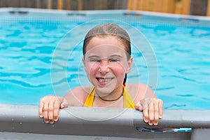 Blond girl swimming in the pool with red cheeks