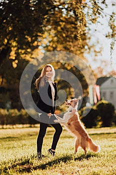 Blond girl train her dog border collie in green park in sunshine