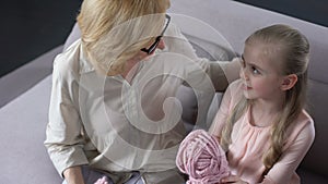Blond grandmother knitting with her little granddaughter at home, handmade