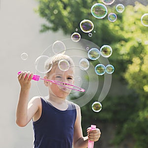 Blond hair boy blowing soap bubbles