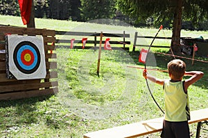 Blond hair kid playing archery during children summer games photo