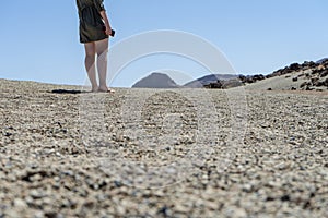 Blond hair teen in relaxing mood at remote lunar, volcanic and arid desert. Back of Spiritual woman in green dress walking alone