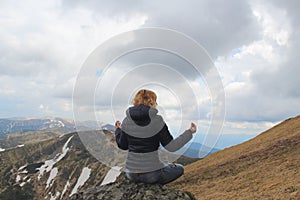 Blond hair woman having a meditation on the mountain peak