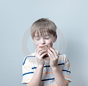 Blond-haired Boy in a striped T-shirt eats a chocolate pancake